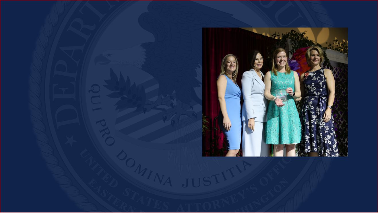 U.S. Attorney Waldref holding an award and standing by 3 women 