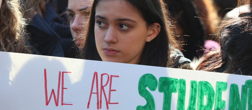 A photo of a demonstration where a student holds a sign that says "we are students"