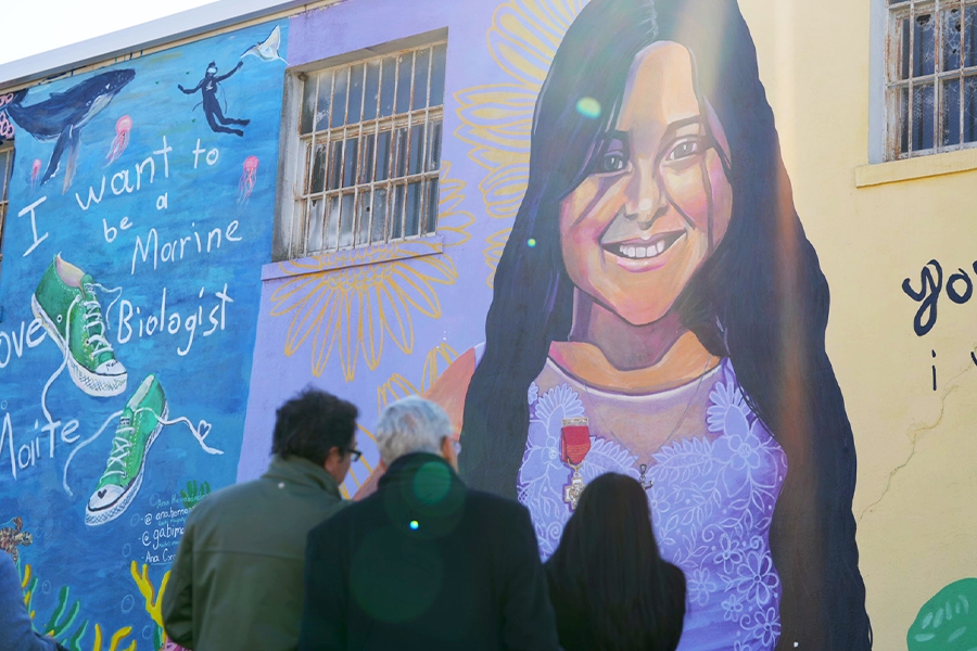 Associate Attorney General Vanita Gupta and Attorney General Merrick B. Garland visited the “Healing Uvalde Mural Project”. The mural shows a pair of green sneakers floating in the ocean, surrounded by a whale and diver with the words “I want to be a marine biologist”. Next to that is a picture of a girl with dark hair surrounded by flowers.