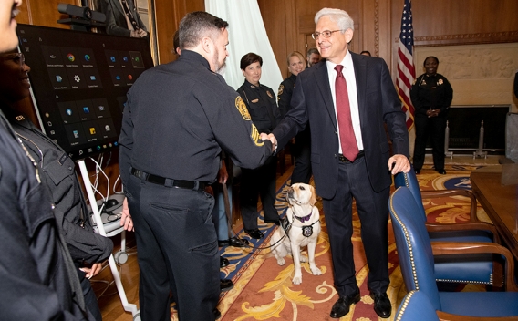 Attorney General Merrick B. Garland shakes hands with a police officer in the Attorney General’s conference room in the Department of Justice
