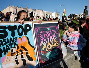 A woman holds a sign that reads, "Stop Asian Hate"