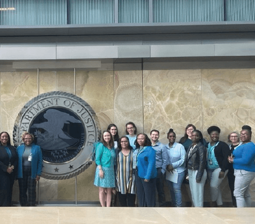 OVW staff take photo in front of Department of Justice Seal