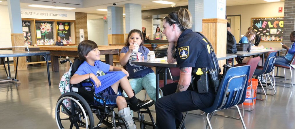A police officer talks with a young boy with a physical disability