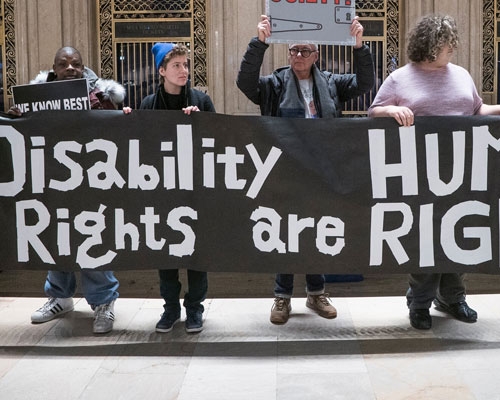 Protesters hold a sign that reads, "Disability Rights are Human Rights".