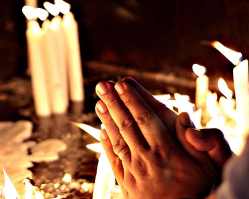 An image of a man praying by candles. 