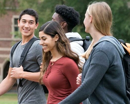 A group of college students walk together on campus. 