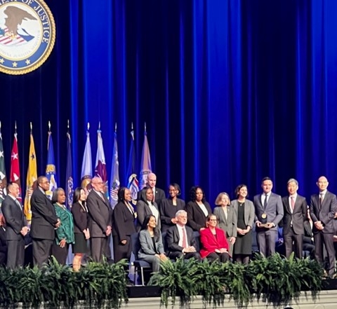 DOJ employees and leadership on the stage of the Attorney General's Award ceremony. 